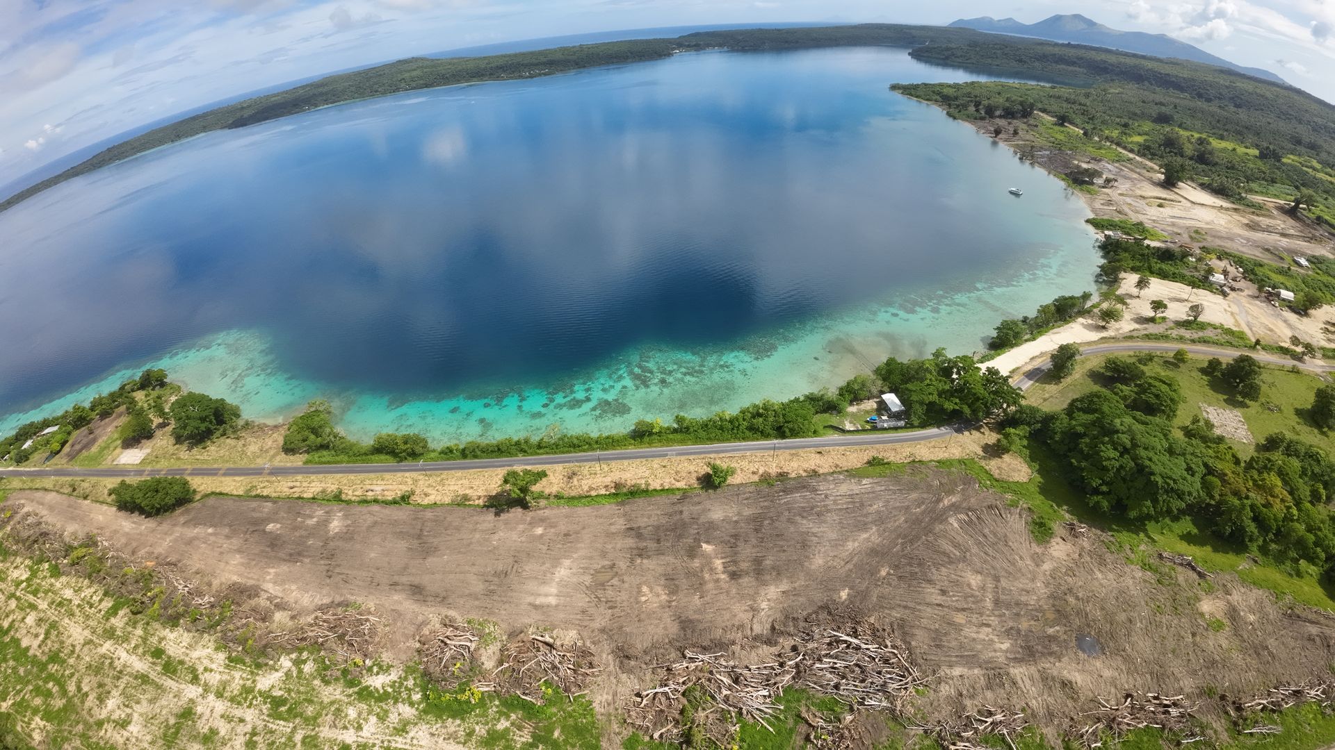 Aerial view over Havannah Harbour. The Efate Ring Road runs along the shoreline, with freshly cleared land for the airside commercial lots between the road and the airstrip in the foreground, and the marina site at the far right.