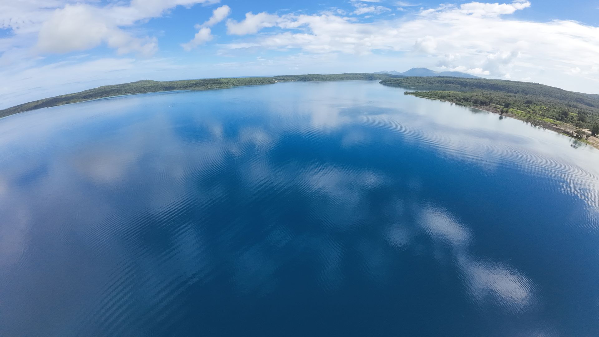 Drone view from above lot 118 across the calm blue water of Havannah Harbour towards Moso Island, with the waterfront marina lots along the shore on the right.